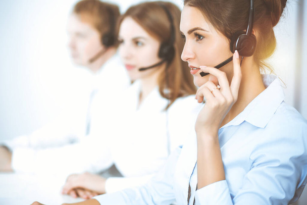 Call center. Focus on beautiful business woman in headset - Foto, Imagen