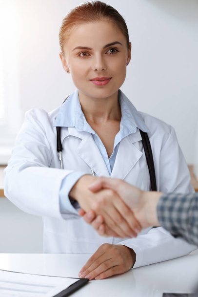 Woman-doctor smiling while shaking hands with her male patient. Medicine concept - Foto, Imagen