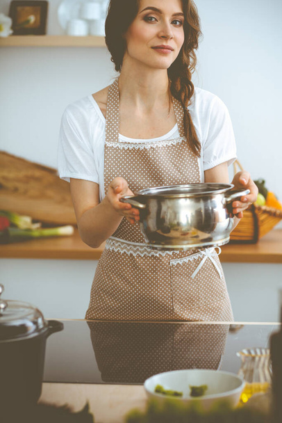 Young brunette woman cooking soup in kitchen. Food and health concept - Foto, Imagen