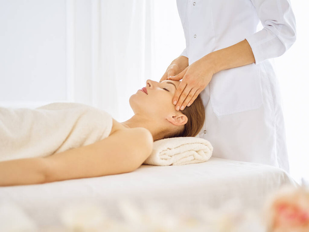 Beautiful woman enjoying facial massage with closed eyes - Foto, afbeelding