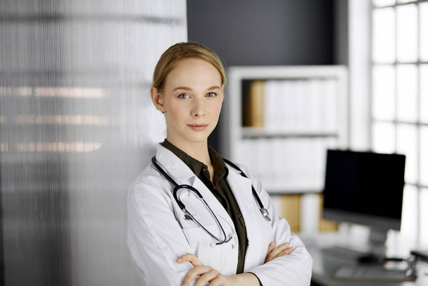 Friendly smiling female doctor standing in clinic. Portrait of friendly physician woman. Perfect medical service in hospital. Medicine concept - Foto, Bild