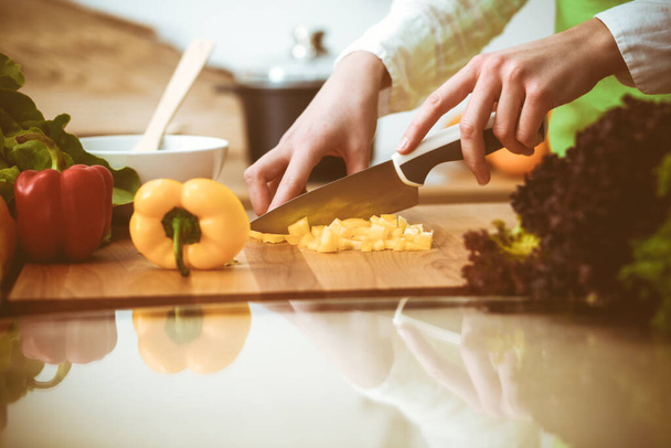 Unknown human hands cooking in kitchen. Woman slicing yellow bell pepper. Healthy meal, and vegetarian food concept - Fotoğraf, Görsel