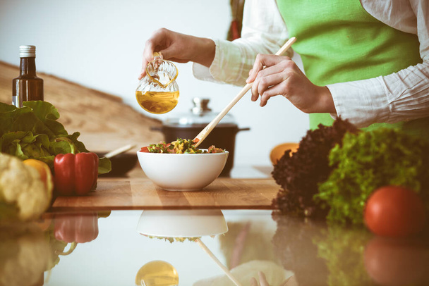 Unknown human hands cooking in kitchen. Woman is busy with vegetable salad. Healthy meal, and vegetarian food concept - Foto, afbeelding