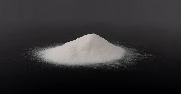 Montón de polvo blanco de bicarbonato de sodio, arcilla o bentonita sobre fondo negro. Productos químicos en polvo como calcio, yeso o yeso Vista lateral - Foto, Imagen
