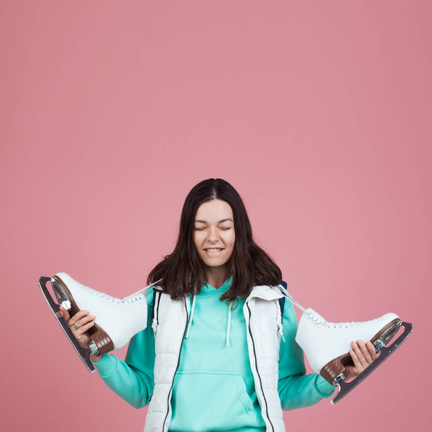 happy and funny girl in a bright hoodie is getting ready to go to the skating rink. Skater with skates on her shoulder - Foto, Imagem