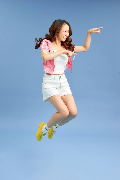 Veselý hipster dívka jumpig s rukama široce rozprostřené na pozadí. Mladá žena ve skoku. - Fotografie, Obrázek