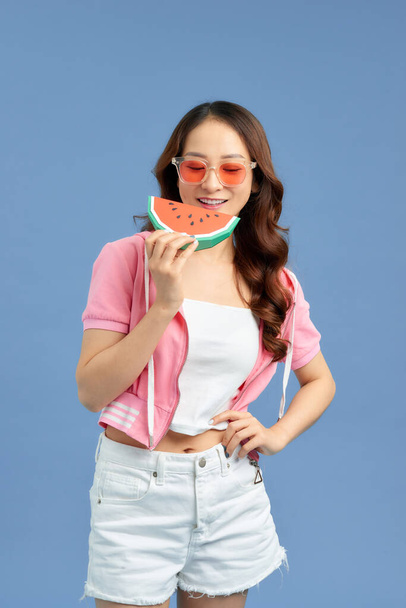 Portret gelukkig vrouw houdt slice van watermeloen over kleurrijke blauwe achtergrond - Foto, afbeelding