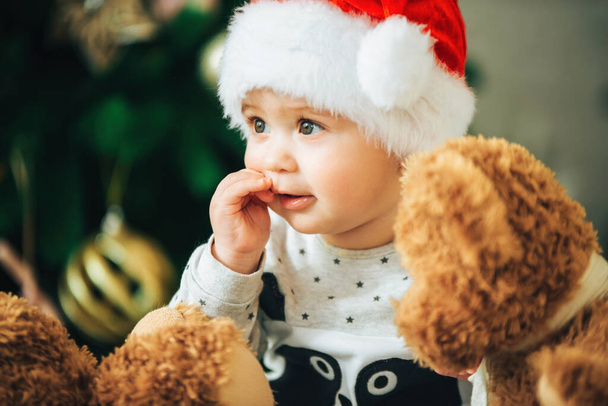 Close up portrait of sweet little baby in christmas hat. New Year. Cheerful one year old kid. - Photo, Image