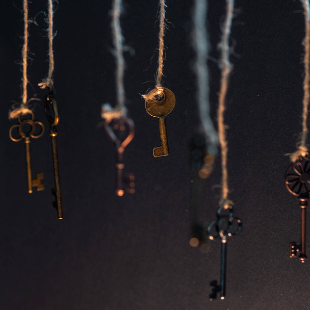 Muchas llaves viejas diferentes de diferentes cerraduras, colgando de la parte superior de las cuerdas. - Foto, imagen