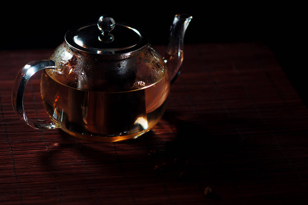 Black tea in a glass teapot. Freshly brewed tea, delicious and healthy hot drink. - Fotó, kép