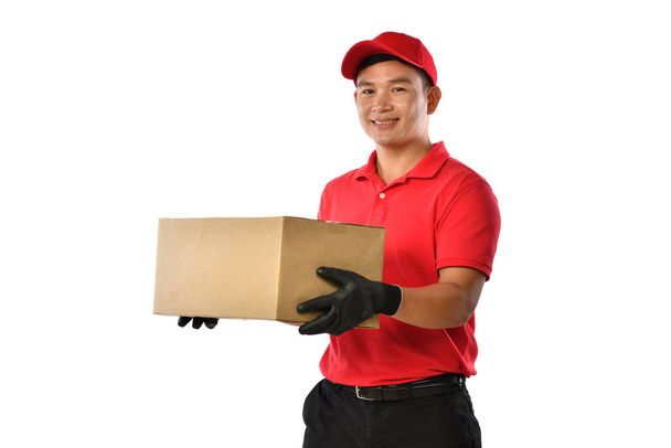 Ασιάτης διανομέας με κόκκινη στολή με χάρτινο κουτί δεμάτων απομονωμένο σε λευκό φόντο - Φωτογραφία, εικόνα