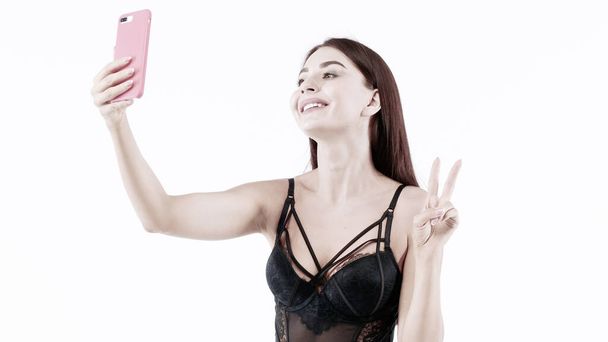 Fitness girl In black Lingerie Making content for her social networks with her body. Studio, isolated image on white background. - Фото, изображение