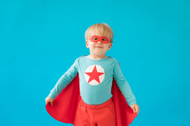 Portrait of superhero child. Super hero kid against blue background. Success and winner concept - Foto, Imagen