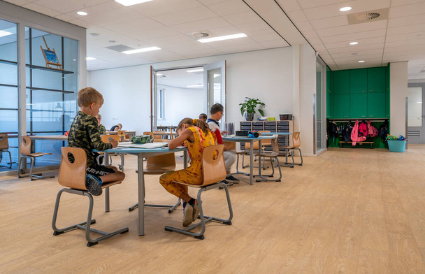 ARNHEM / NIEDERLANDE - 28. AUGUST 2020: Grundschulkinder arbeiten in Gruppen zusammen. Sie befinden sich in einem modernen Schulgebäude - Foto, Bild