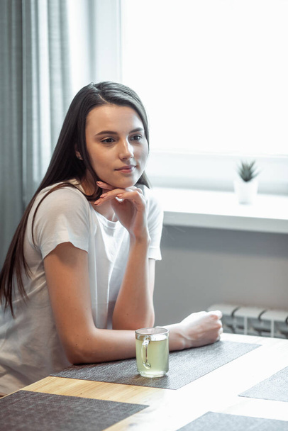 beautiful young woman drinking hot beverage. Attractive girl relaxing at home - Fotografie, Obrázek