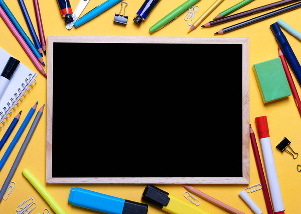 Mockup of Black board, pencils, highlighters, chalks on yellow background - 写真・画像