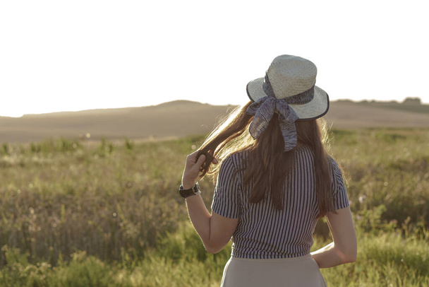 Weiblichkeit, Provence-Stil, Glück, Natur, Sommer, Urlaub - fröhliches junges kaukasisch-slawisches Mädchen mit Strohhut lächelt und ruht auf einem Lavendelfeld bei sommerlichem Sonnenuntergang. Kopierraum - Foto, Bild