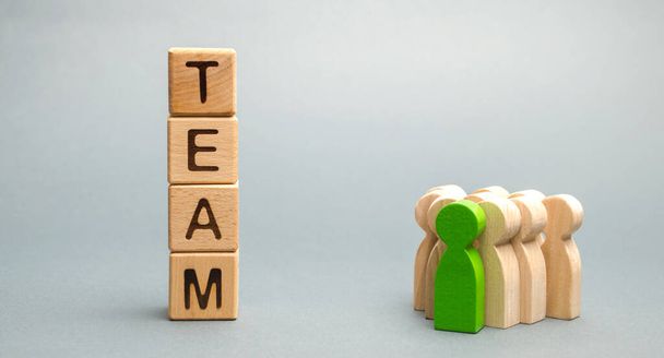 チームとリーダーと労働者の群衆と木製のブロック。強い信頼性のあるビジネスチームの概念。チームワークだ。チーム運営。新しい指導者を選ぶ。木造人物像 - 写真・画像