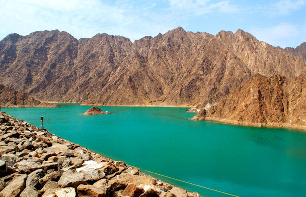 Beautiful deep green Hatta lake with rocky Hajar Mountains on background. Overview of Hatta dam in UAE, Oman. Picturesque nature in the Middle East. - Photo, Image