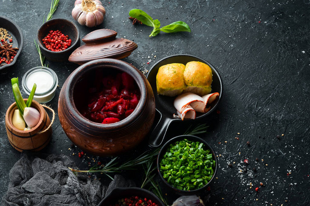 Ukrainian food. Borsch with lard, garlic and donuts on a black stone background. Top view. Rustic style. - 写真・画像