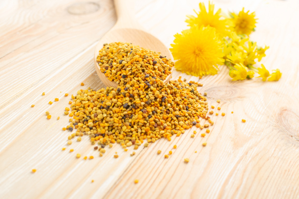 Μακρο πλάνο γύρης μέλισσας ή πέρκας σε ξύλινη κουτάλα σε θολή ρουστίκ φόντο. Ακατέργαστοι καφέ, κίτρινοι, πορτοκαλί και μπλε σπόροι γύρης λουλουδιών ή ψωμί μέλισσας. Υγιή συμπλήρωμα διατροφής με επιλεκτική εστίαση - Φωτογραφία, εικόνα