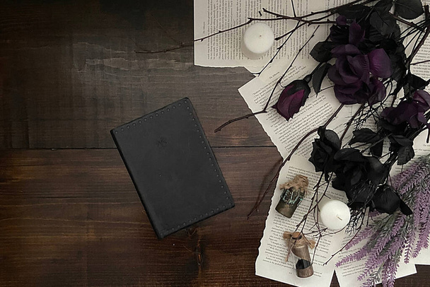 Donkere en heksenachtige gotische houten achtergrond met zwarte bloemen en dagboek - Foto, afbeelding
