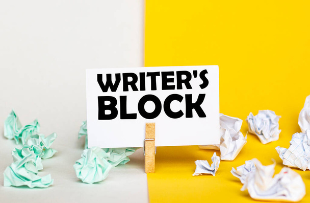 fehér papír szöveges Writer 'S Block egy ruhacsap sárga és fehér hátterű papír köteg különböző színű - Fotó, kép
