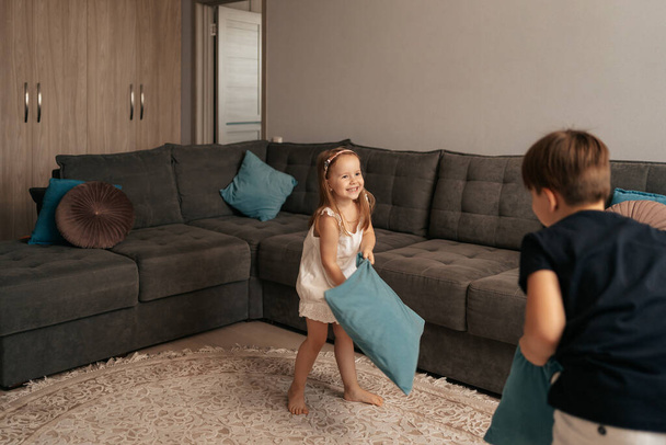 Brother and sister playing with pillows - Фото, изображение