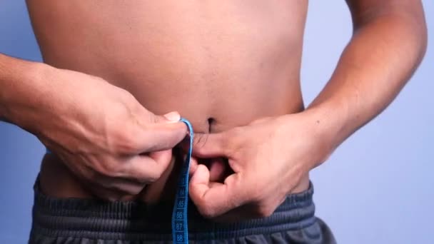 young man measuring his waist with a tape measure, close up. - Footage, Video