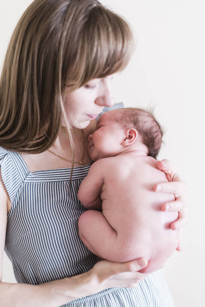 Lifestyle portrait of a young mother and her newborn, three weeks old daughter. - Foto, Imagem