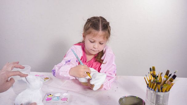 Kleines Mädchen bemalt Papiermaché-Figur im Kunstunterricht. - Foto, Bild