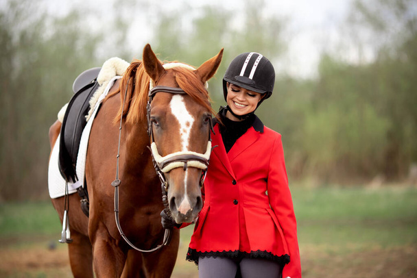 Deporte ecuestre Mujer sonrisa jinete sosteniendo caballo por brida al aire libre - Foto, imagen