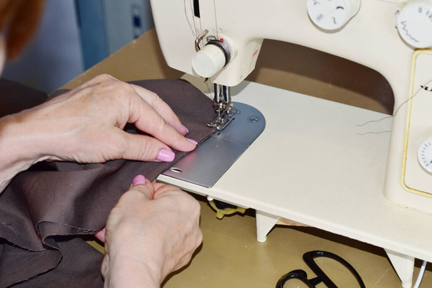 El diseñador de moda cose la ropa en una máquina de coser. - Foto, imagen