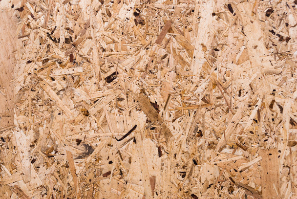OSB boards are made of brown wood chips sanded into a wooden background. Top view of OSB wood veneer background, tight, seamless surface. Oriented Strand Board. Flake board. Sterling board. Aspenite - Valokuva, kuva