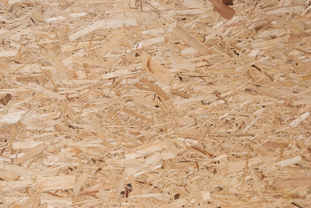 OSB boards are made of brown wood chips sanded into a wooden background. Top view of OSB wood veneer background, tight, seamless surface. Oriented Strand Board. Flake board. Sterling board. Aspenite - Foto, afbeelding