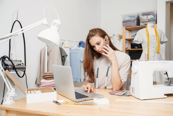 Diseñador de moda costurera mujer trabaja con los clientes en línea, toma llamadas y órdenes para coser ropa - Foto, Imagen