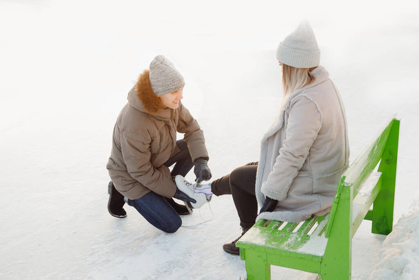 Mann hilft Mädchen Schlittschuhe anziehen für Eisbahn Schnee, Konzept des Winterurlaubs, Familienruhe - Foto, Bild