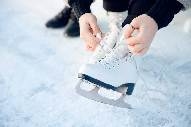A lány cipőfűzőt köt fehér műkorcsolyára télen a jégpályához. Karácsonyi ünnepek fogalma - Fotó, kép