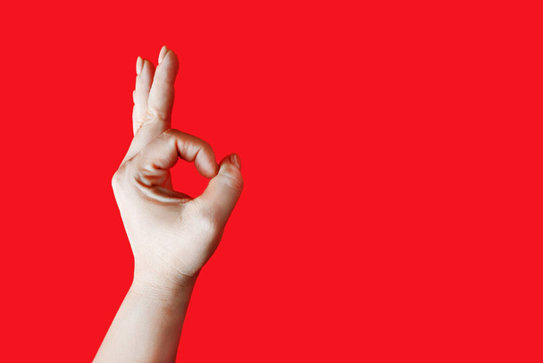 Női kéz mutatja gesztus OK felett piros háttér. Kézjel rendben.. - Fotó, kép