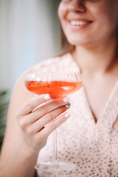 Ernte glückliche Frau lächelt und genießt rosa Alkohol trinken, während sie am Wochenende zu Hause ausruhen - Foto, Bild