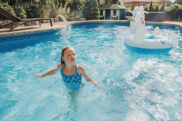 Cute urocza dziewczyna pływanie w basenie na podwórku domu. Dziecko bawiące się w basenie. Letnia aktywność wody na świeżym powietrzu dla dzieci.  - Zdjęcie, obraz