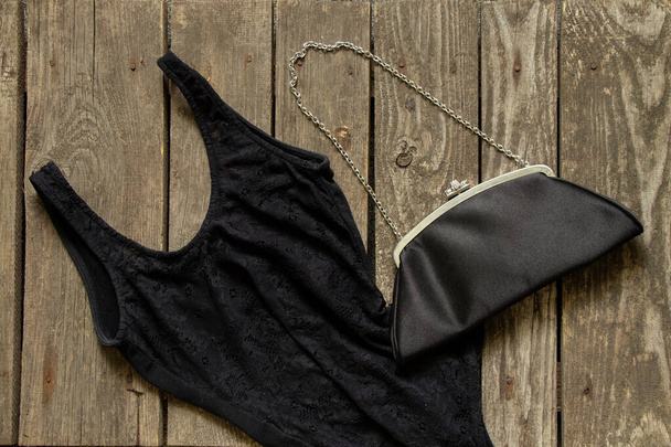 black women's t-shirt and evening bag lies on a wooden background close-up, fashion women - Photo, Image
