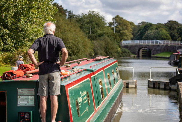 Green & Red Canal Boat navigating a lock on the Kennet and Avon Canal in Devizes, Wiltshire, UK on 5 September 2020 - Photo, Image