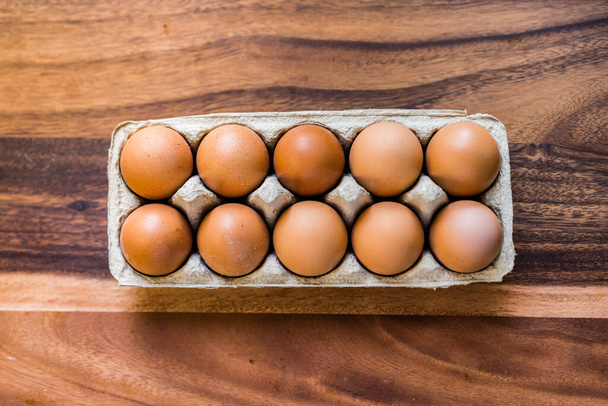 Hele, rauwe eieren in een eierschaal op een houten keukentafel - Foto, afbeelding