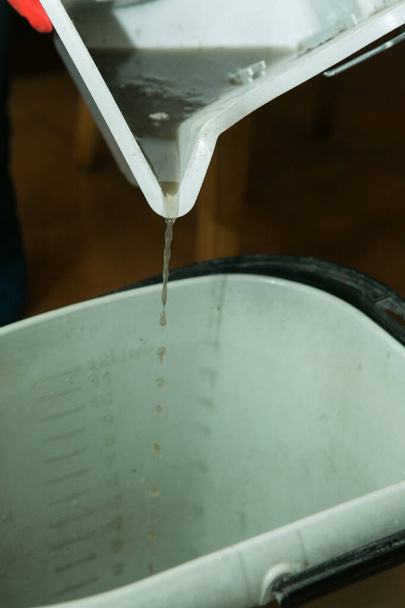 Η διαδικασία καθαρισμού ενός δωματίου με ηλεκτρική σκούπα με ένα aquafilter. Βρώμικο νερό μετά τον καθαρισμό. Αποστράγγιση νερού από το δοχείο. - Φωτογραφία, εικόνα