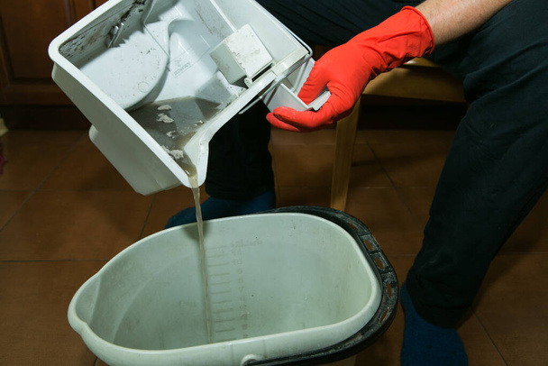 The process of cleaning a room with a vacuum cleaner with an aquafilter. Dirty water after cleaning. Draining water from the container. - 写真・画像