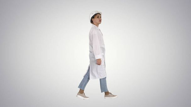 Engineer woman walking and checking the object on gradient background. - Photo, image