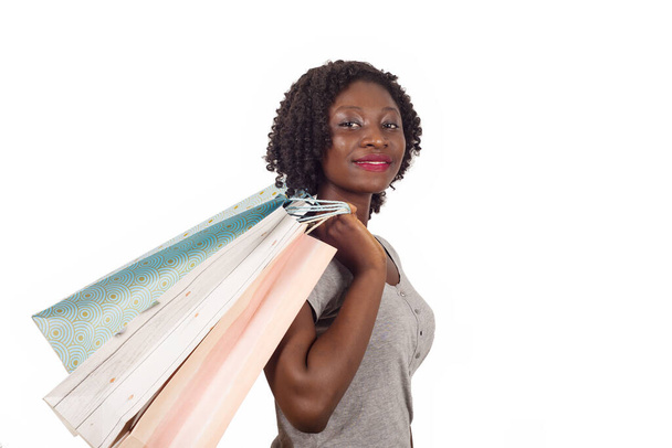 Mujer afroamericana sosteniendo coloridas bolsas de compras, posando sobre blanco. Chica con gran sonrisa, disfrutando de compras compras - Foto, Imagen