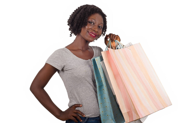 Mujer afroamericana sosteniendo coloridas bolsas de compras, posando sobre blanco. Chica con gran sonrisa, disfrutando de compras compras - Foto, Imagen