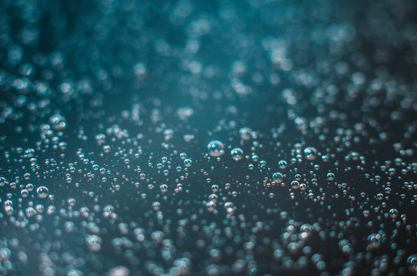 Fondo azul oscuro de burbujas de aire en la superficie del agua. Primer plano de burbujas de aire en líquido. Enfoque selectivo. - Foto, Imagen